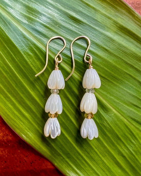 Pair of 3 carved MOP pikake buds with moonstone & citrine rondel stack earring on french earwire laid on Ti leaf background