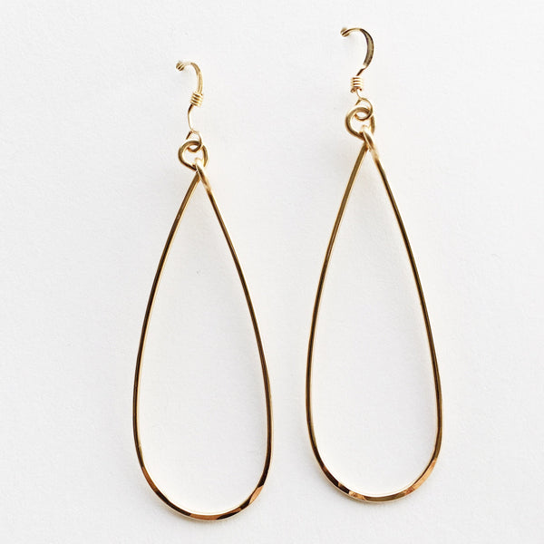 These hoop earrings feature an eye-catching slender teardrop shape with a flattened, light-catching hammered finish along the bottom edge.  Metal: 14K Gold-Filled  Length: 2.5" aprox.